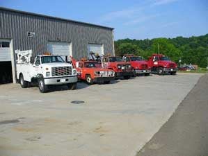 Exterior building with 1 white big truck and 4 red trucks outside